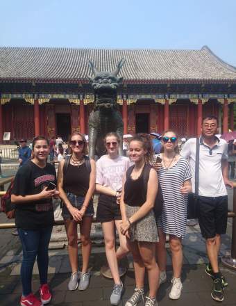 Adolescents devant la statue du dragon de bronze au palais d'été de Pékin (Chine)