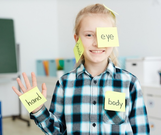 Ecolière apprenant l'anglais avec des post it sur les différentes parties de son corps