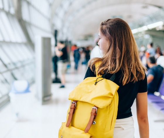 Jeune fille attendant avec un sac jaune son avion pour partir en séjour linguistique