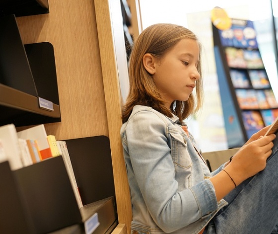 Jeune fille assise dans une librairie avec une bande dessinée