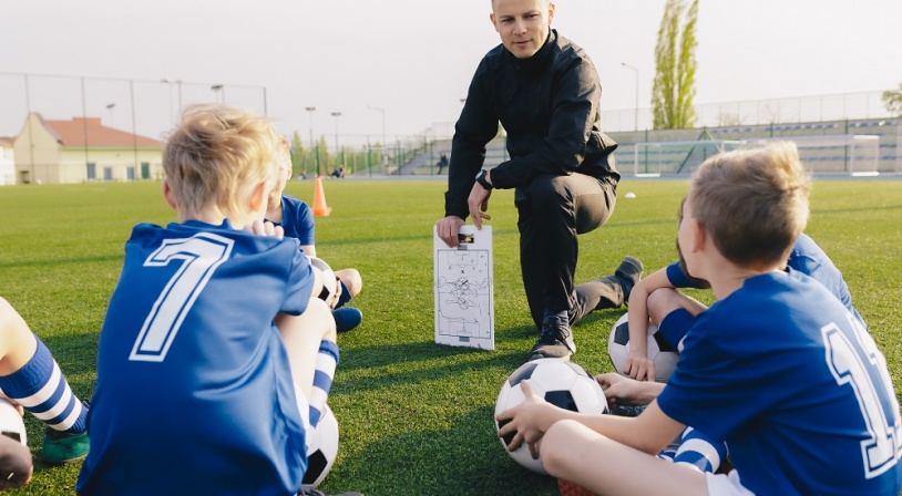 Entraîneur de foot entouré d'enfants