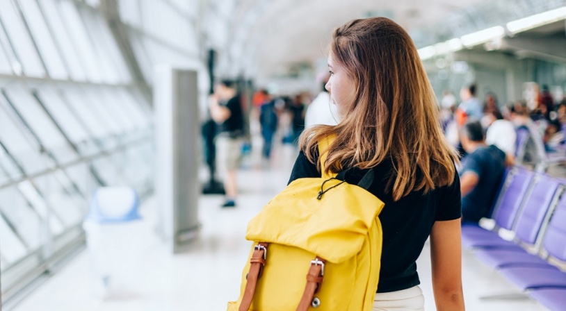 Jeune fille attendant avec un sac jaune son avion pour partir en séjour linguistique