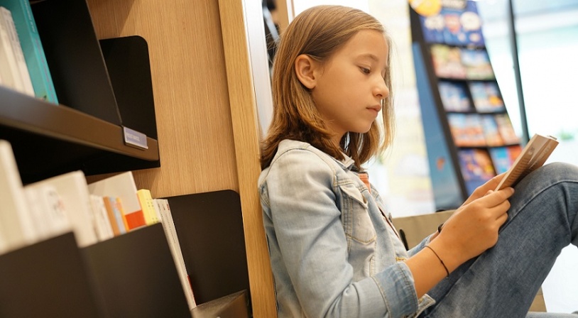 Jeune fille assise dans une librairie avec une bande dessinée