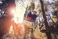 Jeune fille faisant de la tyrolienne dans un parc d'aventure accrobranche
