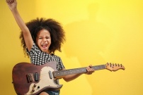 Enfant jouant de la guitare électrique Jeune fille métisse jouant de la guitare électrique